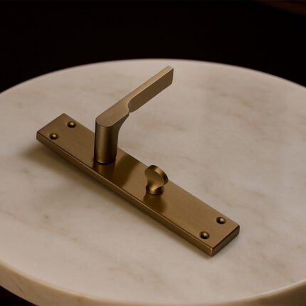 TIDLO 502 Satin sheen gold bathroom door handle placed on a circular marble surface