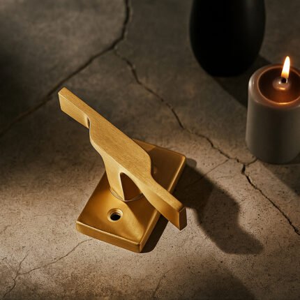 TIDLO 502 gold window handle placed on a concrete surface and behind it a candle