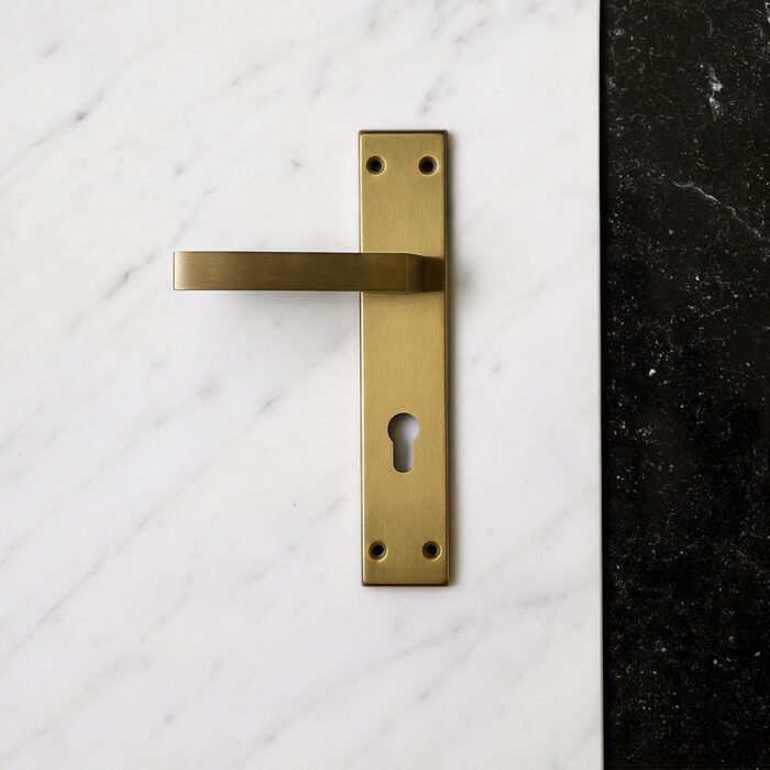 TIDLO 505 backplate Gold cylinder door handle placed on a white marble surface